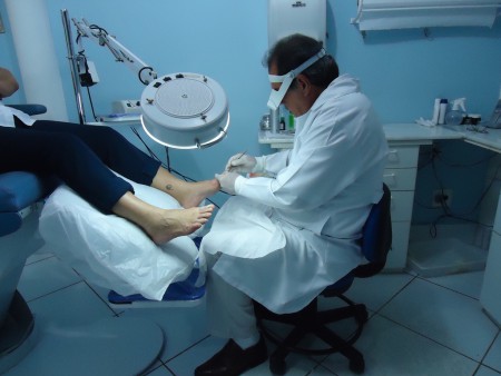 Profissional podólogo prestando atendimento técnico e minucioso ao paciente no consultório